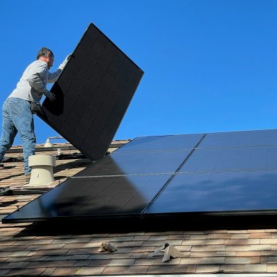 man in white dress shirt and blue denim jeans sitting on white and black solar panel